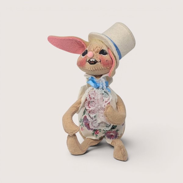 1993 Annalee felt Easter bunny doll wearing a white top hat and floral lace vest against a neutral backdrop.