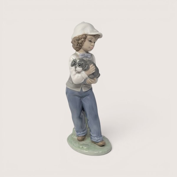 Vintage Nao by Lladro glossy porcelain figurine of a young boy in a cap holding a small grey puppy.