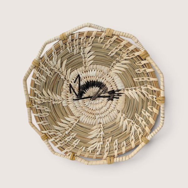 Vintage Tohono O'Odham hand-woven coiled pine needle basket plate featuring a central stitched motif.