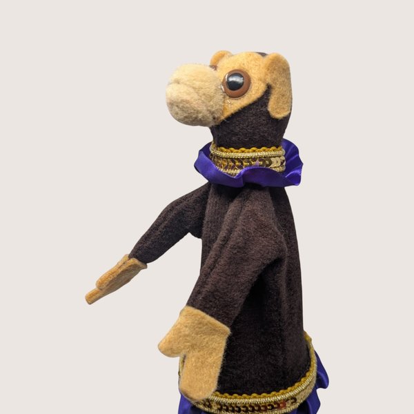 Vintage handmade felt monkey stick puppet with purple ruffled trim and gold sequins on a wooden rod.