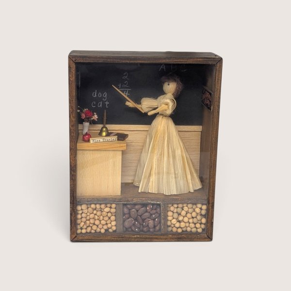 Vintage wooden shadow box diorama featuring a corn husk doll teacher, a blackboard, and compartments filled with dried beans.