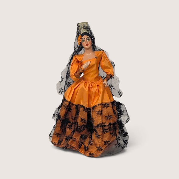 Vintage Spanish senorita doll wearing an orange dress with black lace trim and a matching veil.