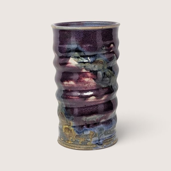 1980s handmade stoneware ribbed vase featuring a rich flowing glaze in deep purple, blue, and earthy tones.