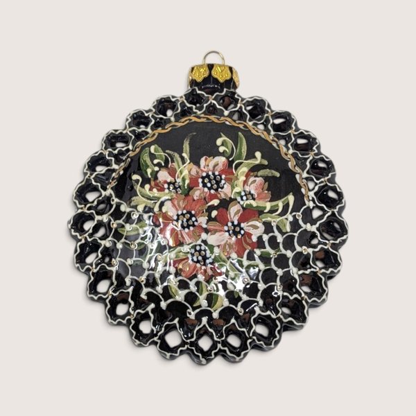 Vintage round handpainted black clay Christmas ornament with floral design and pierced lace border