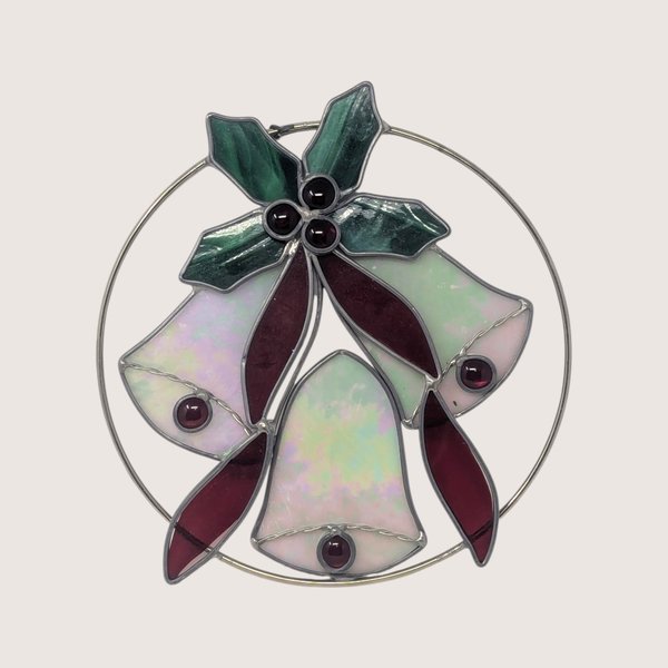 Vintage iridescent stained glass Christmas bells suncatcher featuring green holly leaves and deep red jewel accents.