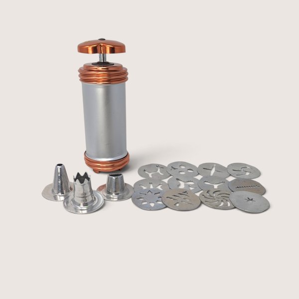 Vintage Mirro aluminum cookie press with copper-tone accents, 12 pattern disks, and 3 icing tips.