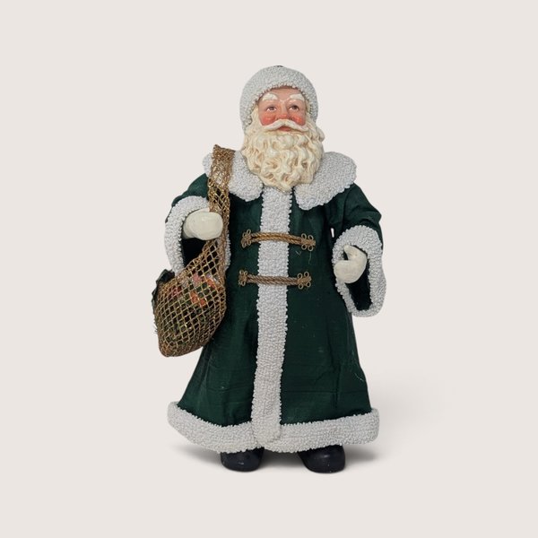 Vintage 1993 Clothique Possible Dreams Santa figurine wearing a green coat with white trim and carrying a net bag.
