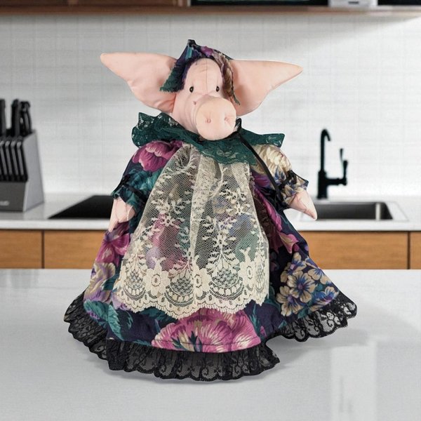 A plush fabric pig doll dressed in a Victorian-style floral gown with a cream lace apron and black lace trim. The pig has large pointed ears and wears a matching floral bonnet with green lace detailing.