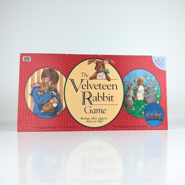 Rectangular red game box featuring three circular vignettes. Left shows a child hugging a toy rabbit, center displays the title in serif font with a rabbit illustration, and right depicts three rabbits in a meadow. A small inset shows four miniature rabbit dolls.