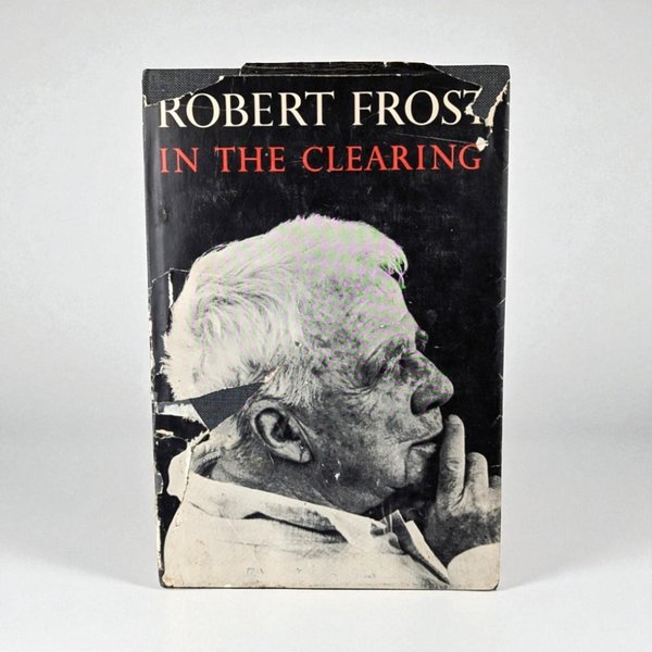 A black-and-white profile portrait of Robert Frost on a book cover. The title In the Clearing is printed in red. The dust jacket shows significant wear and tearing along the top and left edges, revealing the dark textured binding underneath.