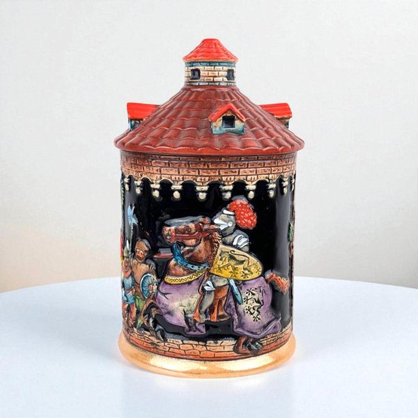Cylindrical ceramic jar shaped like a medieval turret with a conical red-tiled roof lid. High-relief carvings depict a knight in armor on a caparisoned horse against a black background. Earthy tones of gold, purple, and brown feature glossy glazes.