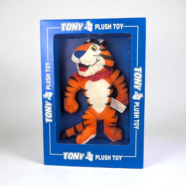 An 8-inch plush Tony the Tiger figure standing inside its original blue cardboard display box. The tiger has vibrant orange fur with black stripes, a white snout and chest, and a signature red bandana. The plush has a soft, fuzzy texture and a muscular silhouette, posed with a cheerful expression.
