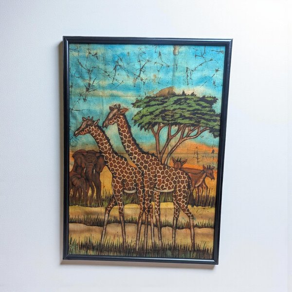 A large-scale batik fabric painting featuring two giraffes in the foreground against a savanna backdrop with elephants and an acacia tree. The textile displays a crackled wax-resist texture in shades of turquoise, amber, and earth brown.