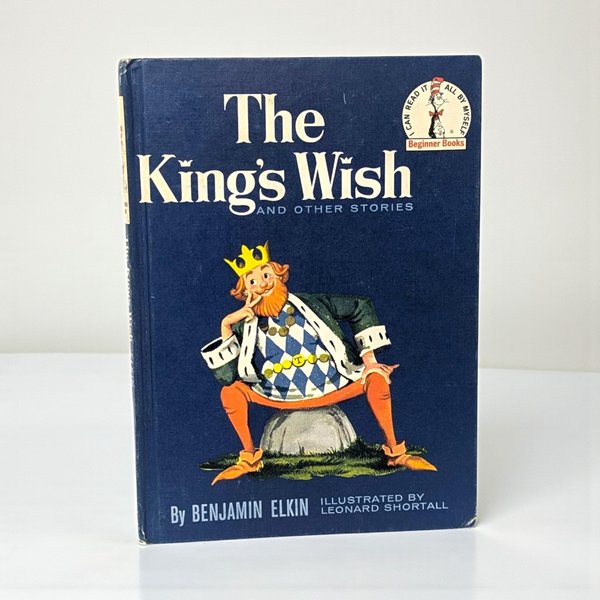 A landscape-oriented hardcover book with a thin purple border. The cream cover features a central circular illustration of a large family of bears in blue and red clothing crowded into a tufted yellow armchair.