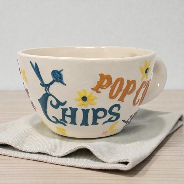 Large ceramic mug featuring a handpainted design with the Pop Chips logo in bold red and blue lettering. The piece has a wide, sturdy handle and a glossy cream-colored glaze.