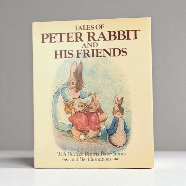 The cover of Tales of Peter Rabbit and His Friends features a cream-colored background with a soft watercolor illustration of five rabbits. Mrs. Rabbit wears a blue apron and carries a basket, while Peter stands nearby in his signature blue jacket.