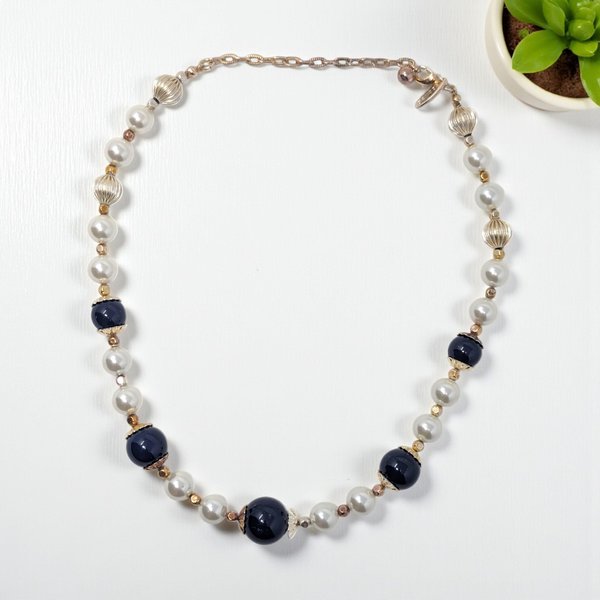 A vibrant 18-inch single-strand necklace featuring high-quality glass beads. The design alternates between deep cobalt blue rounds, crisp opaque white beads, and polished gold-tone spacers. 