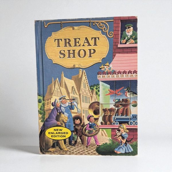 Vintage hardcover children's book titled Treat Shop. The cover features a colorful mid-century illustration of a village toy shop with characters including a lion, a sea captain, and children. The palette is dominated by blue, red, and yellow tones.