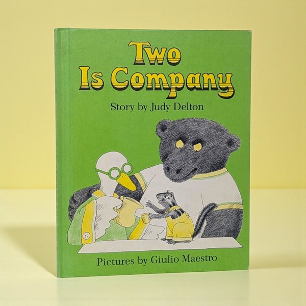 Bright green hardcover book featuring a large black bear in a white shirt, a white duck with green glasses, and a small chipmunk. They are gathered around a table with yellow cups.