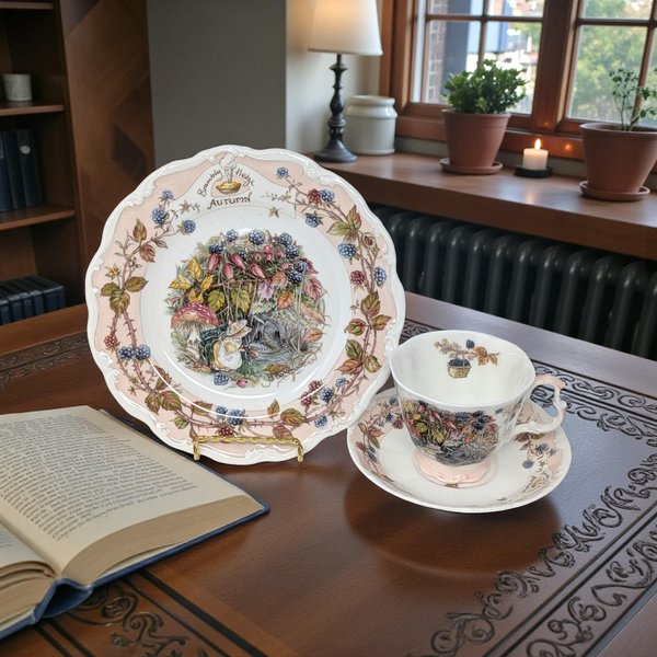 A three-piece ceramic tea set featuring intricate illustrations of mice among autumn berries and brambles. The scalloped edges are bordered in soft pink with trailing blackberry vines and thorns against a creamy white background.